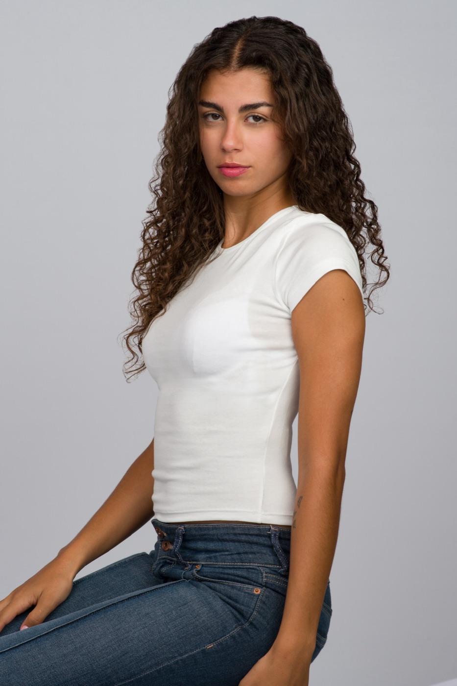 Vitoria sentada de perfil con camiseta blanca y vaquero
